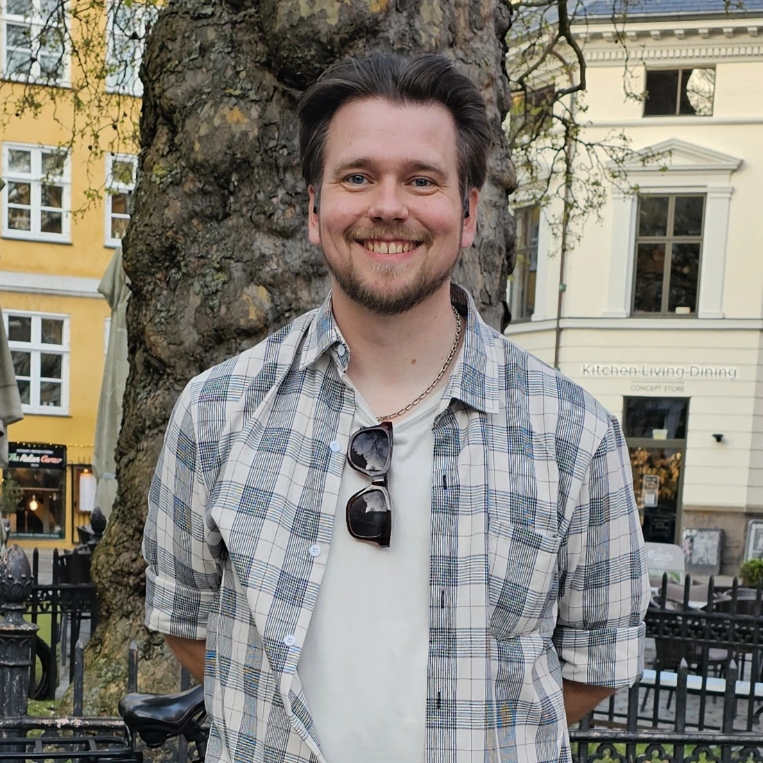 DM Daniel smiling outdoors beside a tree